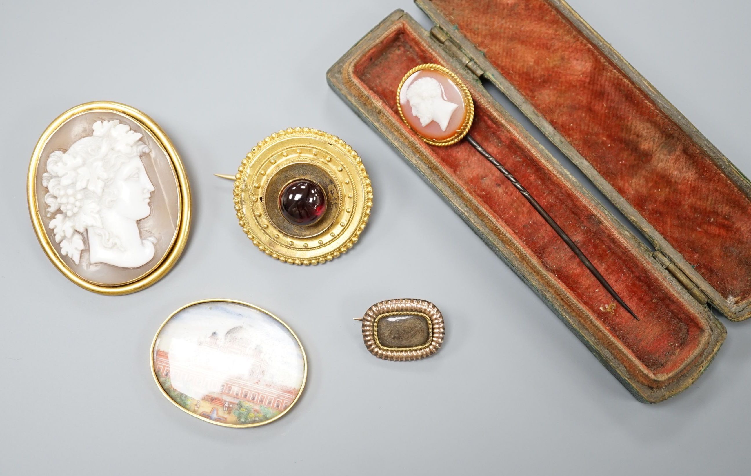 A Victorian yellow metal and cabochon garnet set circular brooch, 31mm, gross 9.3 grams, a stick pin with yellow metal and hardstone cameo set terminal, a mounted Indian miniature, a mounted cameo shell brooch and a Vict